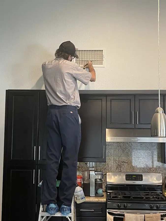 Technician inspecting an air vent during HVAC service in Northfield